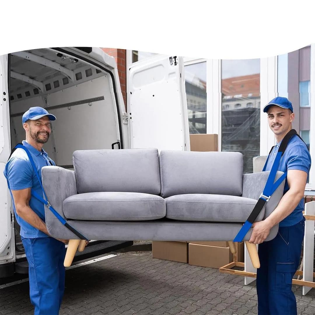 Två flyttare i blått bär en grå soffa ur en flyttbil