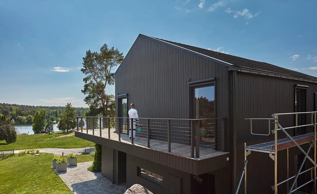 Nymålad mörk fasad på en villa med byggnadsställning