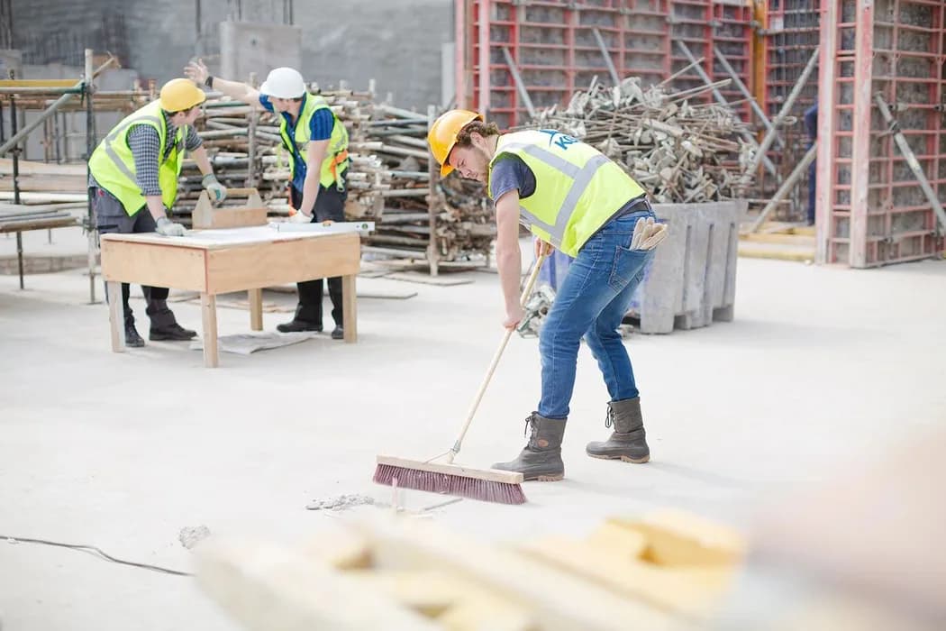 Byggstädare sopar golvet i en lokal efter renovering