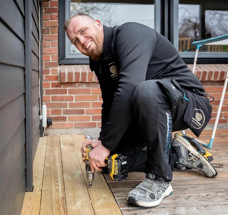 Snickare skruvar fast trallbrädor på ett trädäck